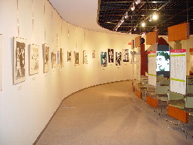 白壁に沢山の絵画が展示されている山本ふるさと文化館の展示会場内の写真