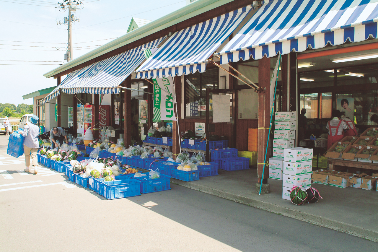 お店の軒先にコンテナに入った沢山の野菜や果物の商品が並んでいるドラゴンフレッシュセンターの店舗前の写真